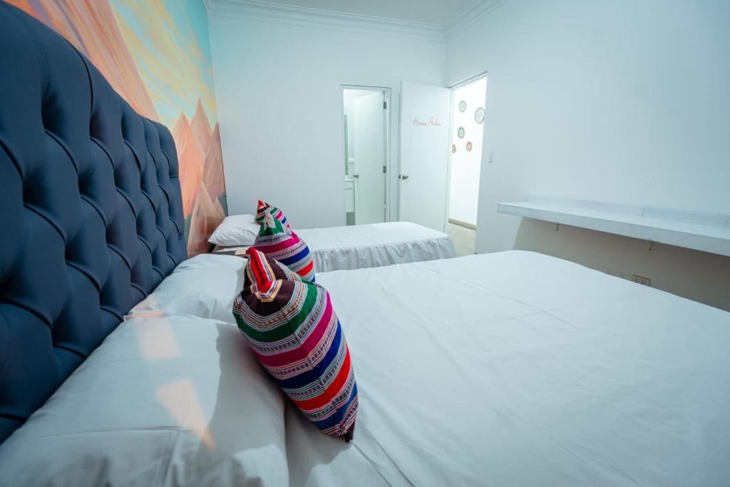 Habitación privada con dos camas, ropa de cama blanca y cojines de tejido andino