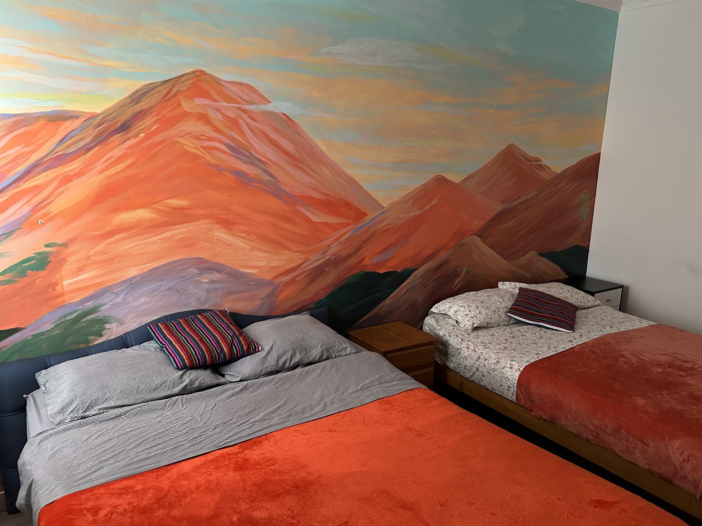 Mural de montañas andinas al atardecer pintado a mano sobre la pared de una habitación