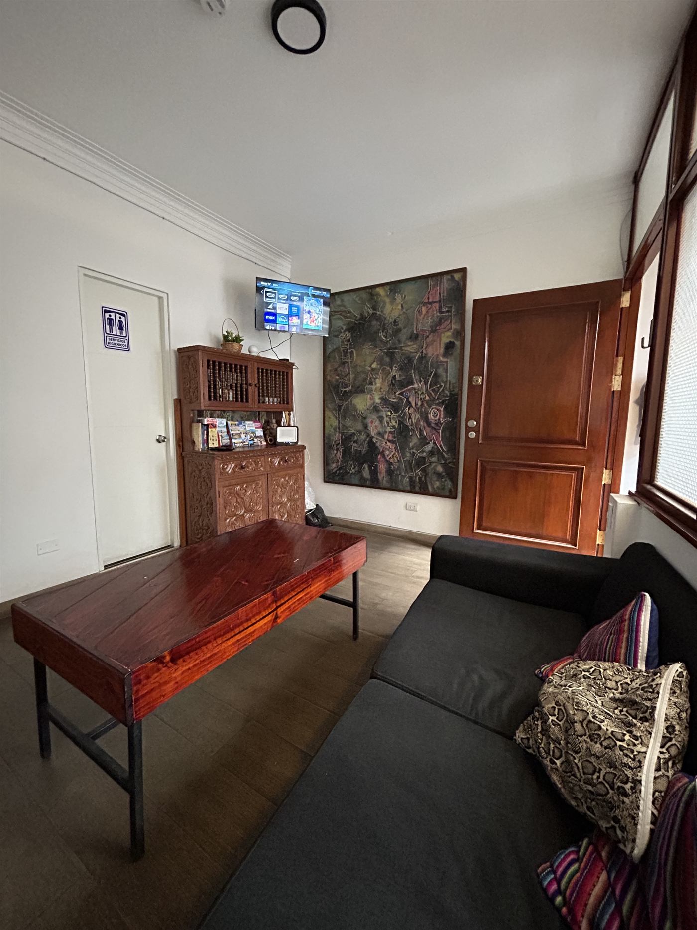 Sala común con sofá, mesa de madera, televisor y un cuadro grande de arte contemporáneo
